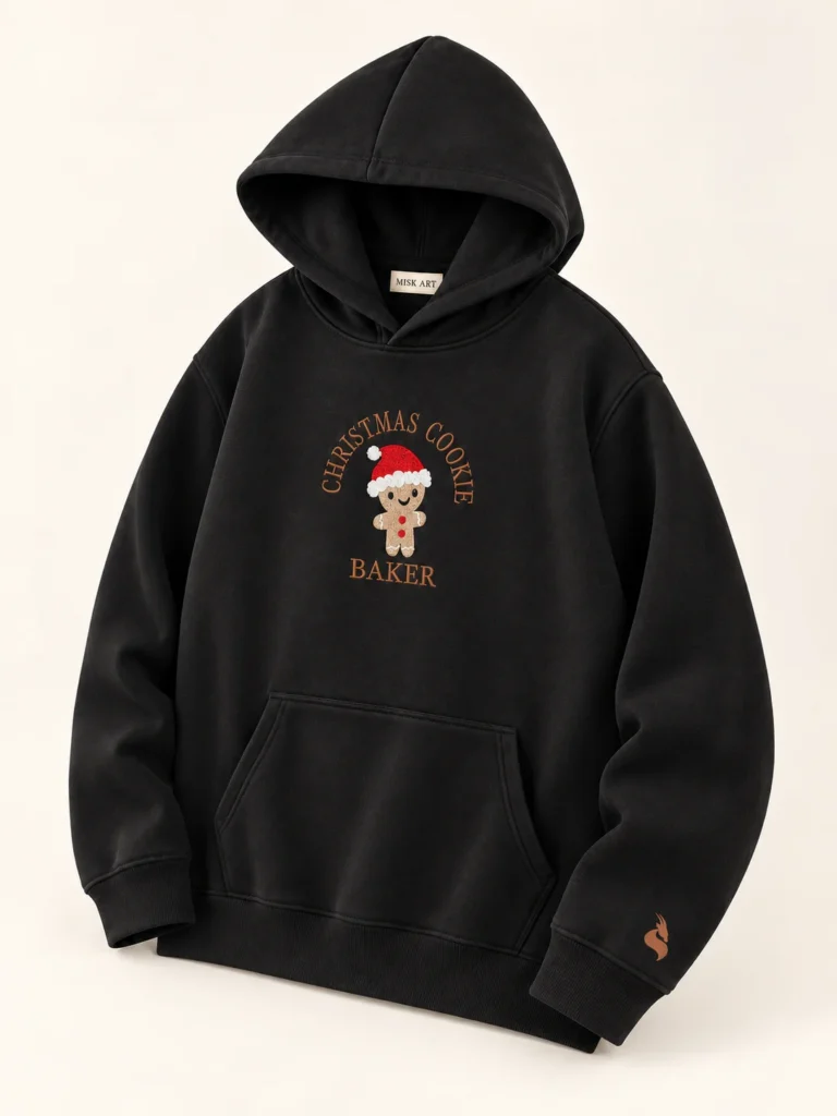 MISK ART Christmas Cookie Baker Hoodie – Black Detail, gazelle branding on an ivory studio background